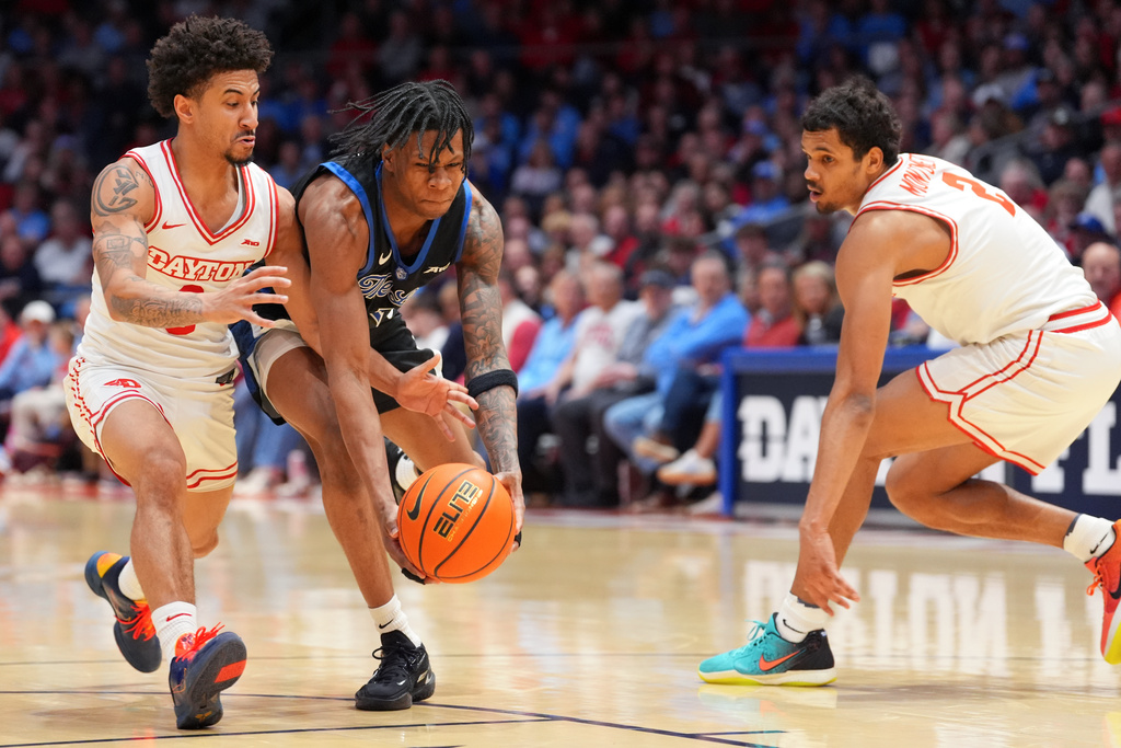 Saint Louis' Quentin Jones (1), center, drives to the basket as Dayton's Javon Bennett (0), left, and De'shayne Montgomery (2), right, defend during the first half of an NCAA college basketball game, Tuesday, Feb. 24, 2026, in Dayton, Ohio. (AP Photo/Kareem Elgazzar)