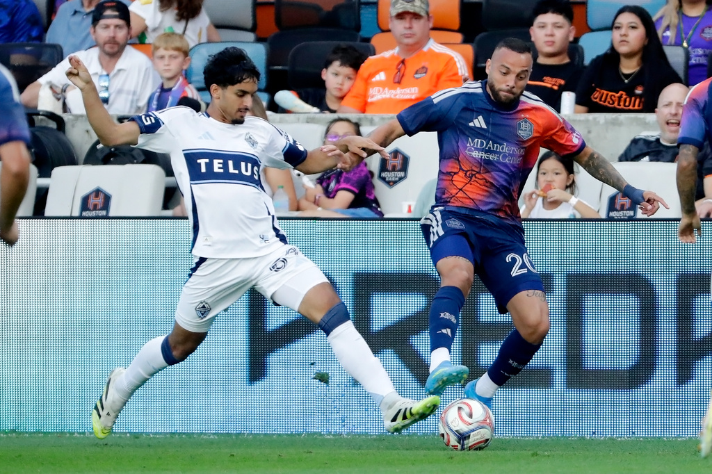 Vancouver Whitecaps FC midfielder Jeevan Badwal, left, attempts to steal the ball from Houston Dynamo FC midfielder Guilherme Santos during the first half of an MLS soccer match, Saturday, May 16, 2026, in Houston. (AP Photo/Michael Wyke)