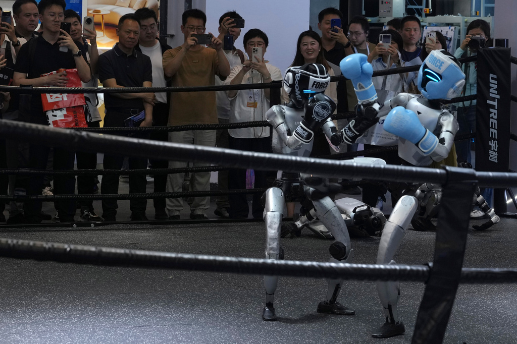 Visitors watch robots box at a booth for leading Chinese commercial humanoid robotics firm Unitree Robotics during the World AI Conference in Shanghai, China, on July 17, 2026. (AP Photo/Ng Han Guan)