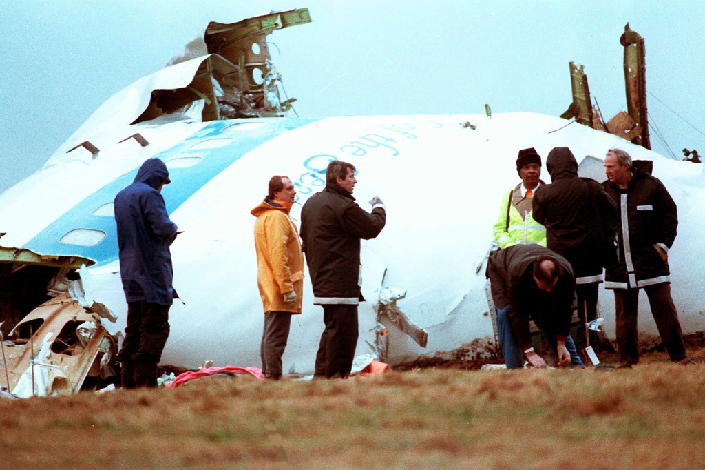 FILE - Unidentified crash investigators inspect the nose section of the crashed Pan Am flight 103, a Boeing 747 airliner in a field near Lockerbie, Scotland, Dec. 23, 1988. (AP Photo/Dave Caulkin, File)