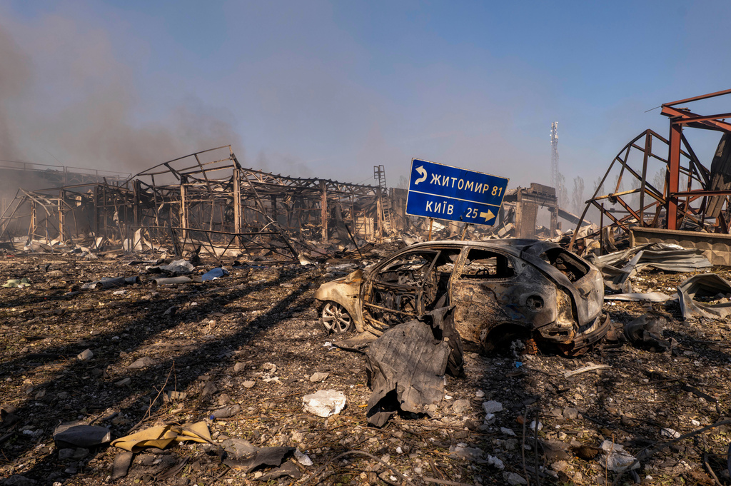 A view of a destroyed car amid damaged buildings, with a road sign showing the direction and distance to Kyiv and Zhytomyr after a Russian attack struck a warehouse, followed by an explosion, in the village of Myla, Kyiv region, Ukraine, Saturday, Aug. 29, 2026. (AP Photo/Dan Bashakov)