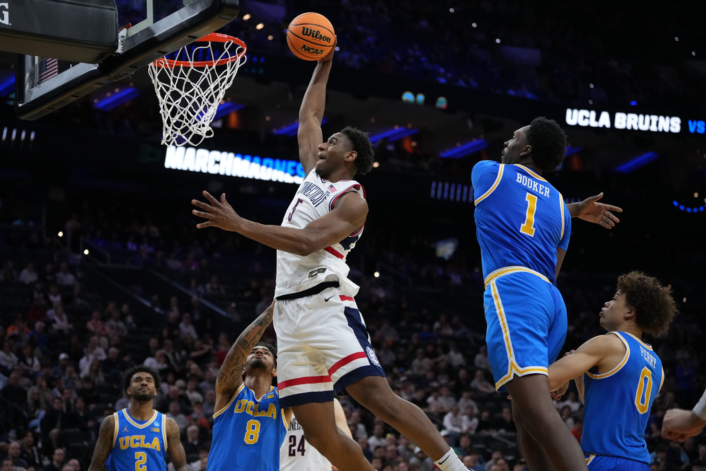 UConn's Tarris Reed Jr. (5) goes up for a dunk [ast UCLA's Xavier Booker (1) and Eric Freeny (8) during the second half in the second round of the NCAA college basketball tournament, Sunday, March 22, 2026, in Philadelphia. (AP Photo/Matt Slocum)