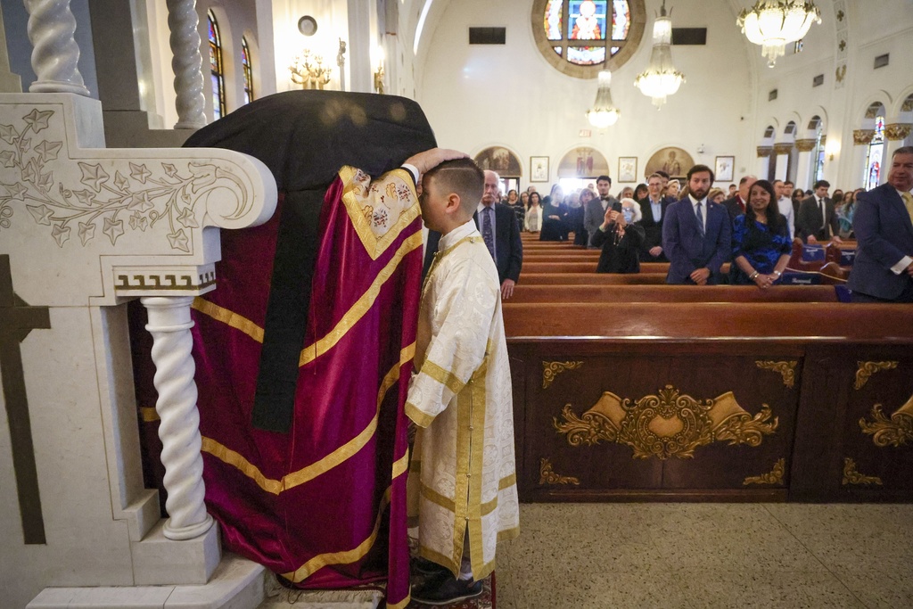 His Eminence Archbishop Elpidophoros of the Greek Orthodox Archdiocese of America, left, blesses altar boy Fotie Amoriginos, 9, of Holiday, at the Saint Nicholas Greek Orthodox Cathedral during the 120th Epiphany celebration on Tuesday, Jan 6, 2026, in Tarpon Springs, Fla. (Jefferee Woo /Tampa Bay Times via AP)