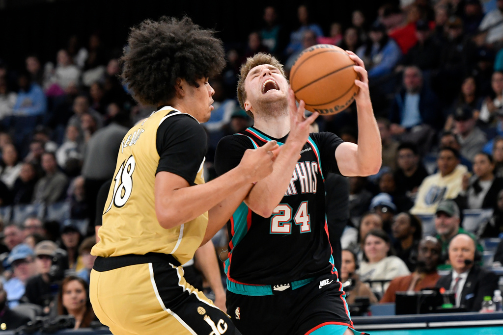 Memphis Grizzlies guard Cam Spencer (24) handles the ball against Washington Wizards forward Kyshawn George (18) in the first half of an NBA basketball game Saturday, Dec. 20, 2025, in Memphis, Tenn. (AP Photo/Brandon Dill)