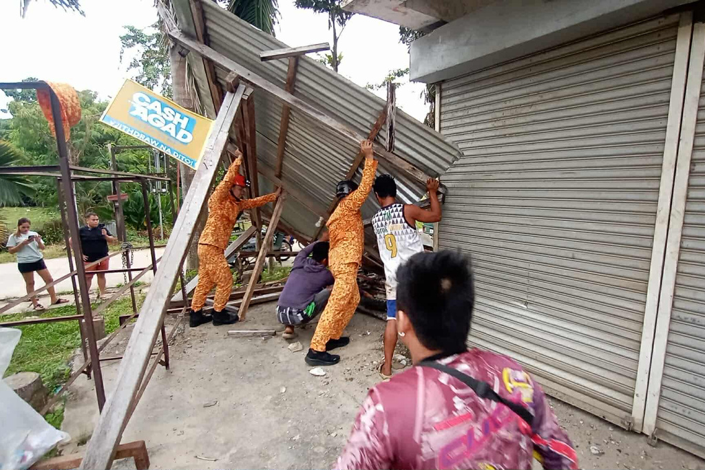 In this photo provided by the Bureau of Fire Protection, firefighters and residents hold on a toppled structure following a strong earthquake in Davao Oriental province, southern Philippines on Friday Oct. 10, 2025. (Bureau of Fire Protection via AP)