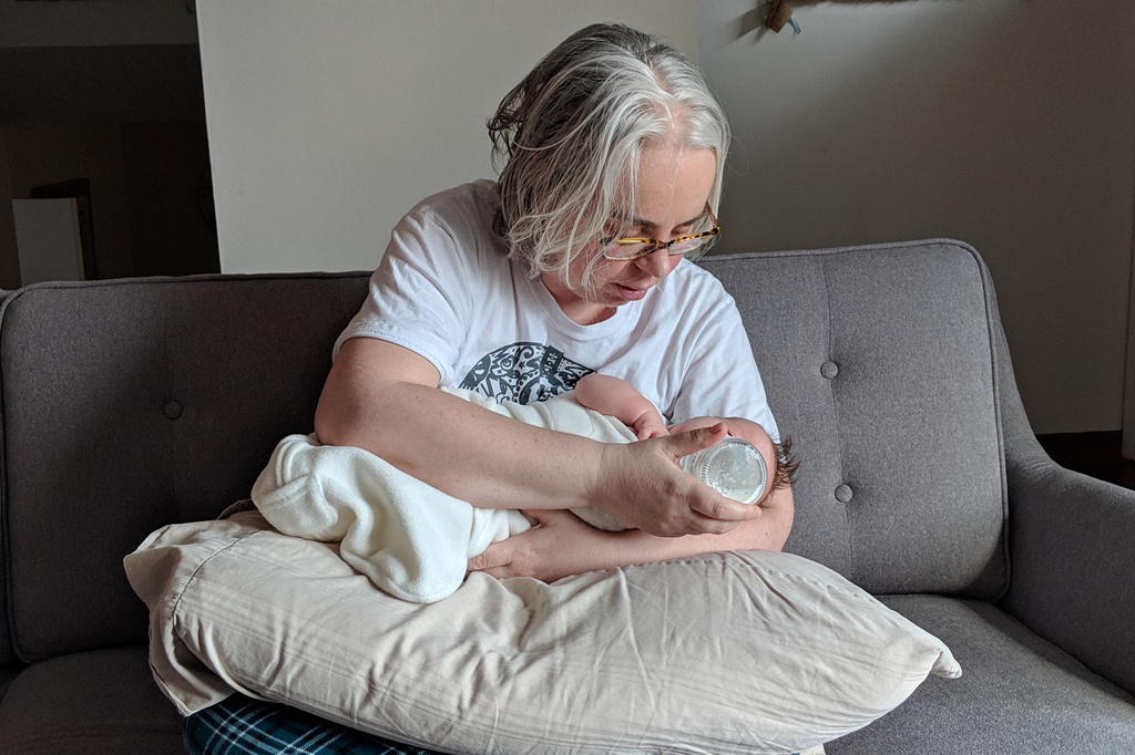 This photo provided by James Fitzsimmons shows Bridget María Chesterton cradling her infant daughter on her couch in Grand Island, N.Y., March 20, 2019. (James Fitzsimmons via AP)