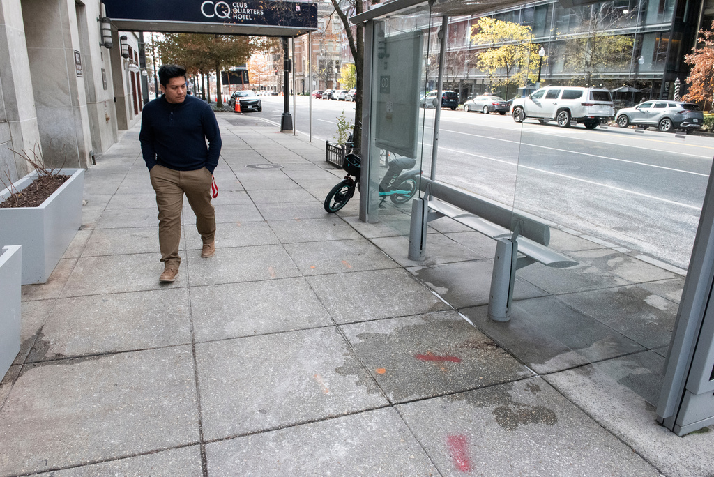 A man walks past blood stains, which have been partially washed away, one day after two National Guard soldiers were shot near the White House in Washington, Thursday, Nov. 27, 2025. (AP Photo/Cliff Owen)