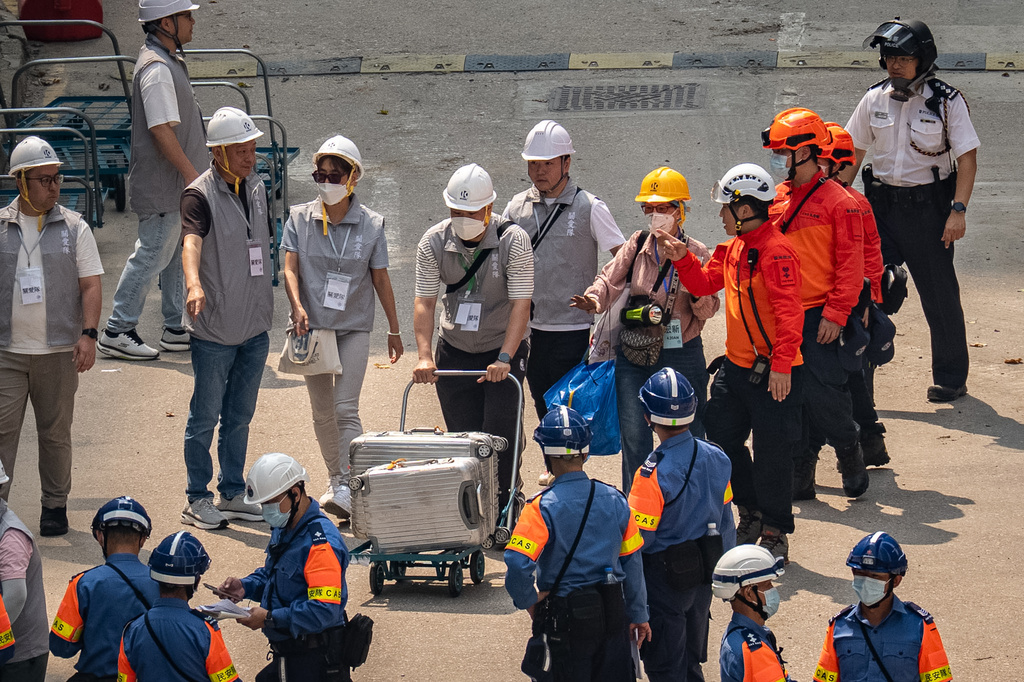 Government workers assist residents of Wang Fuk Court to retrieve their belongings as they return to their flat five months after a deadly fire in Hong Kong Monday, April 20, 2026. (AP Photo/Chan Long Hei)
