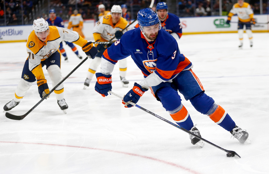 New York Islanders defenseman Adam Pelech, right, controls the puck in front of Nashville Predators forward Matthew Wood during the first period of an NHL hockey game Saturday, Jan. 31, 2026, in Elmont, N.Y. (AP Photo/John Munson)
