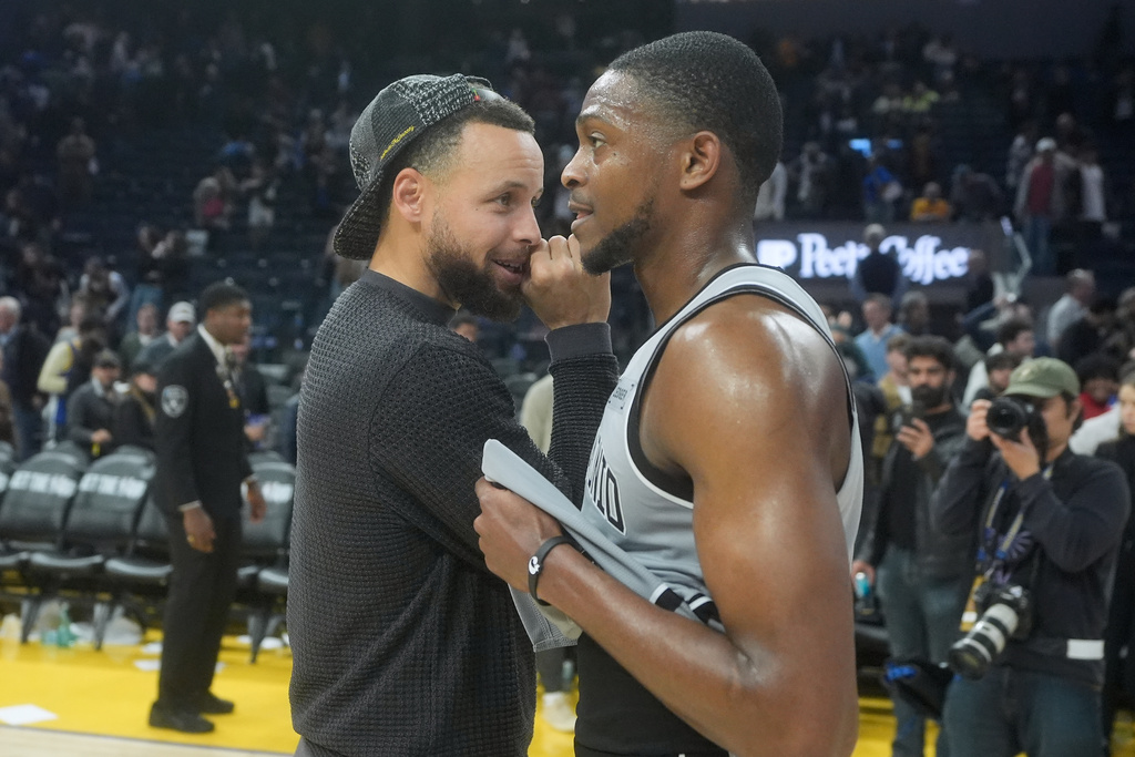 Injured Golden State Warriors guard Stephen Curry, left, talks with San Antonio Spurs guard De'Aaron Fox after an NBA basketball game in San Francisco, Wednesday, Feb. 11, 2026. (AP Photo/Jeff Chiu)