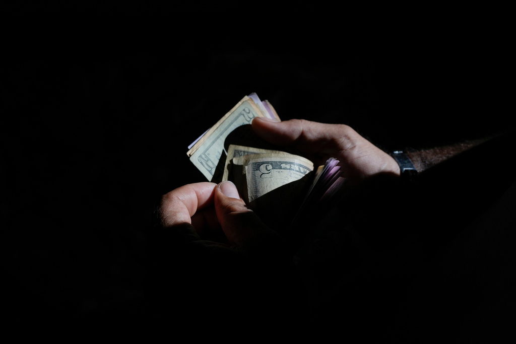 Butcher Richard Lazcano counts U.S. dollar bills to pay for a bus to the Colombian border, where he will sell meat he bought at Las Pulgas market in Maracaibo, Venezuela, June 19, 2025. Lazcano returned to his old job after his attempt to reach the United States was cut short when the Trump administration suspended asylum appointments. (AP Photo/Matias Delacroix)