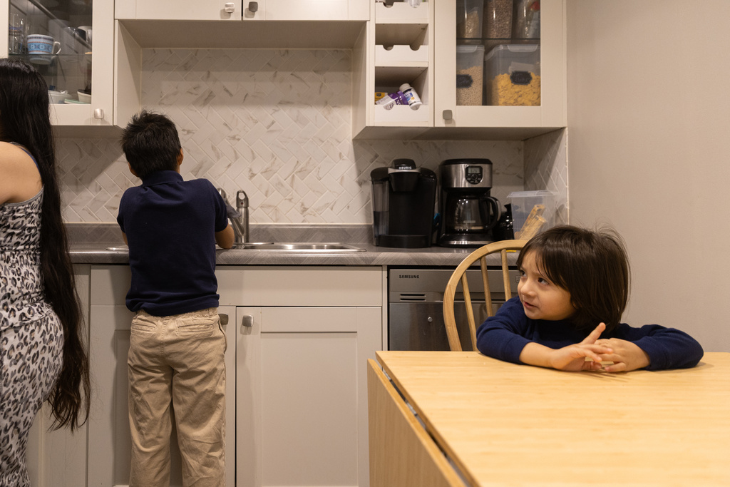 Yair, 3, right, waits for his mom to prepare breakfast while his brother Giancarlo, 10, washes his hands Tuesday, Feb. 3, 2026, in Minneapolis. (AP Photo/Liam James Doyle)