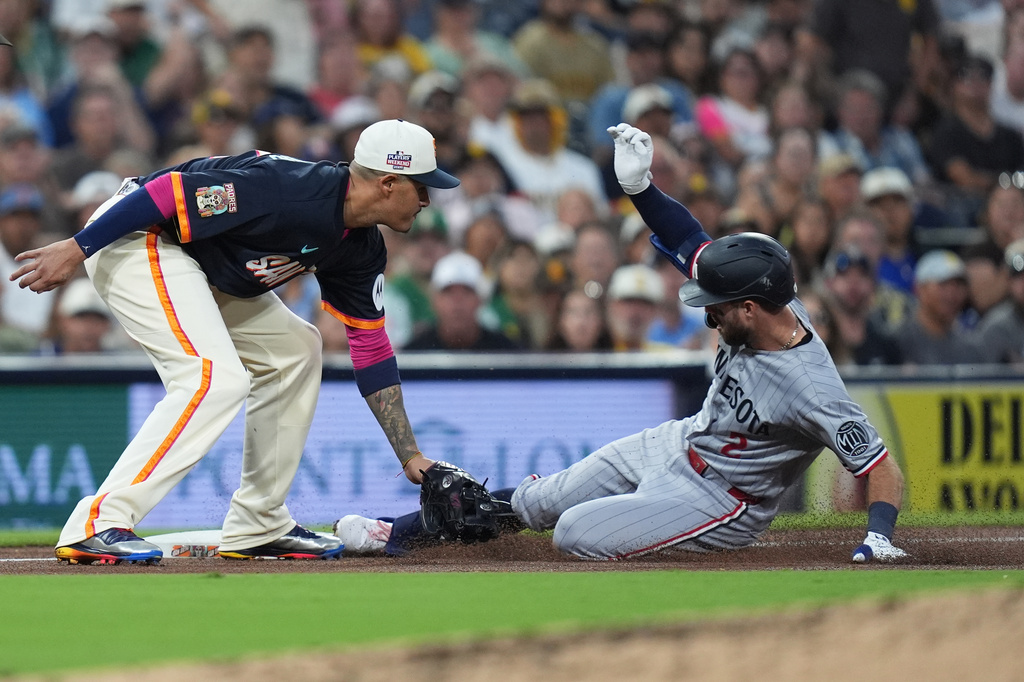 Minnesota Twins' Kody Clemens, arrives safely to third base after hitting a two-RBI triple as San Diego Padres third baseman Manny Machado is late with the tag during the fourth inning of a baseball game Friday, Aug. 21, 2026, in San Diego. (AP Photo/Gregory Bull)