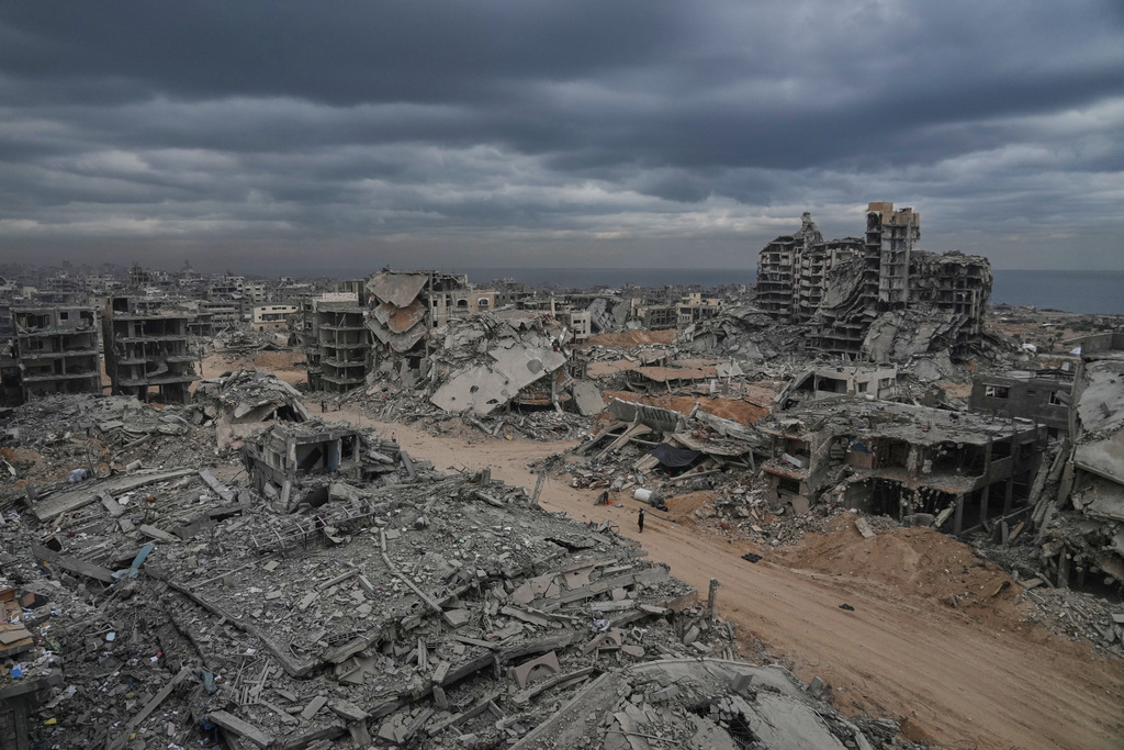 Displaced Palestinians walk amid destroyed buildings in the Shati refugee camp in Gaza City, Sunday, Oct. 12, 2025, after Israel and Hamas agreed to a pause in their war and the release of the remaining hostages. (AP Photo/Abdel Kareem Hana)