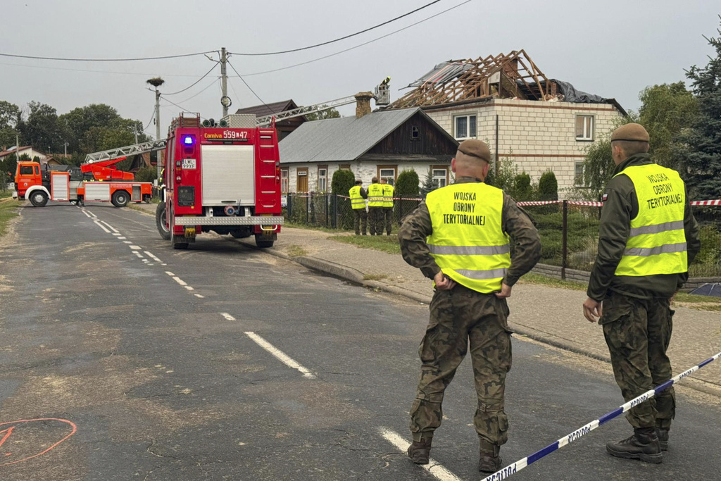 Firefighters and territorial defence officers stand close to the destroyed roof of a house, after Russian drones violated Polish airspace during an attack on Ukraine, in Wyryki near Lublin, Poland, Thursday, Sept. 11, 2025. (AP Photo/Rafal Niedzielski)
