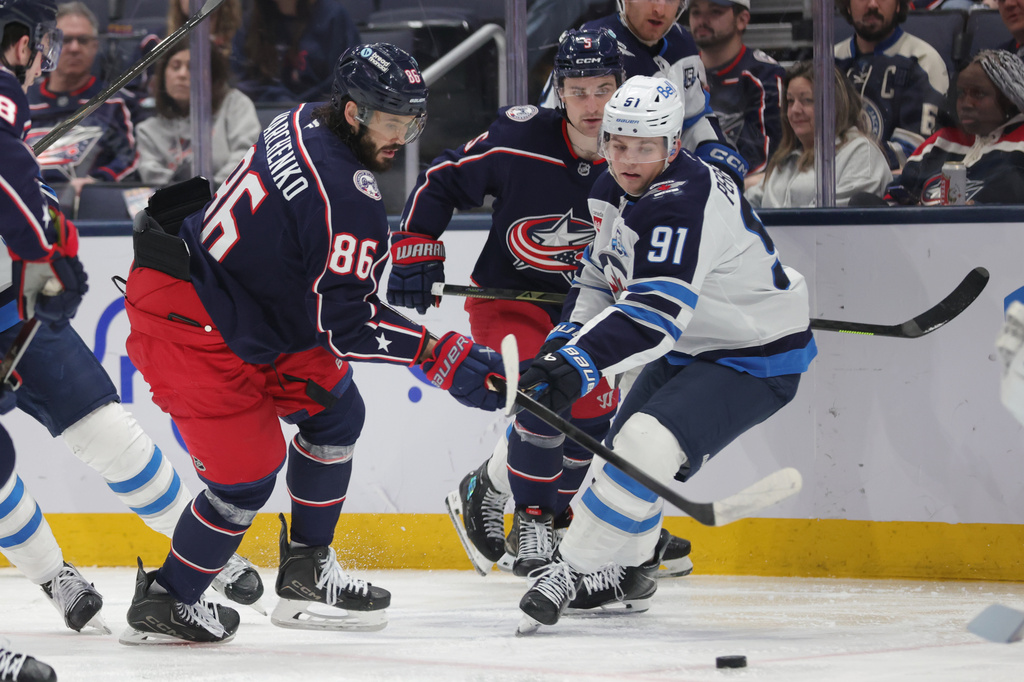Columbus Blue Jackets forward Kirill Marchenko (86) reaches for the puck in front of Winnipeg Jets forward Cole Perfetti (91) during the second period of an NHL hockey game in Columbus, Ohio, Saturday, April 4, 2026. (AP Photo/Paul Vernon)