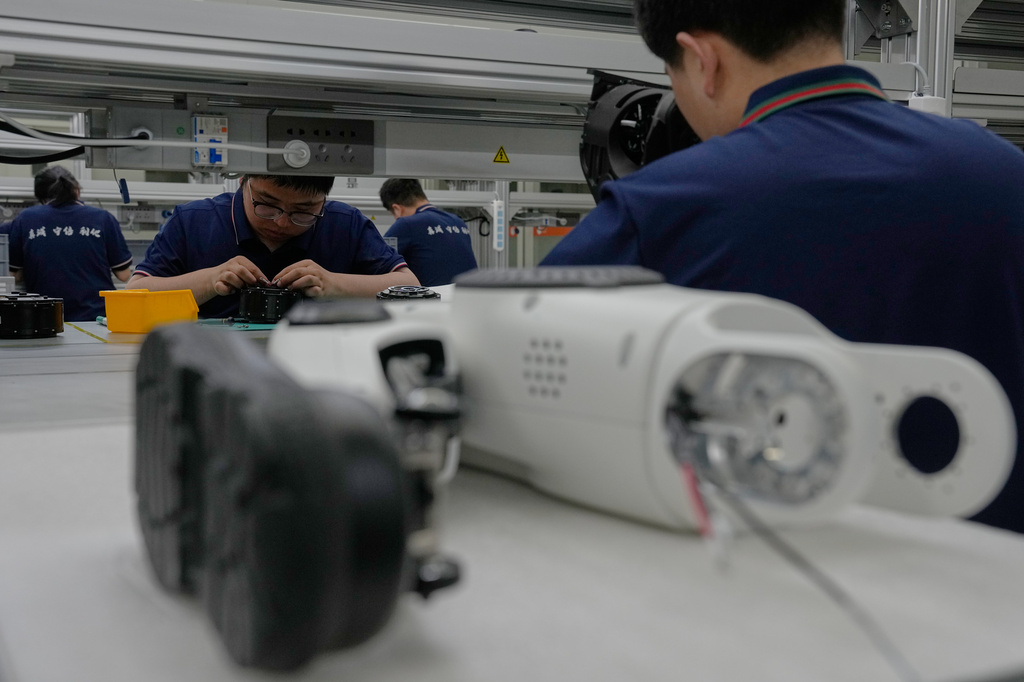 Workers assemble robot legs components at the LY iTech Beijing Super Factory for Embodied Artificial Intelligence during a media tour in the Beijing E-Town on the outskirts of Beijing on May 29, 2026. (AP Photo/Andy Wong)