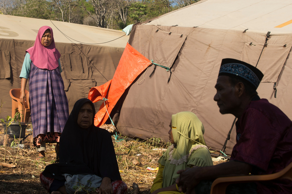 People sit outside makeshift tents where they take shelter following an earthquake in North Lamba Leda, East Nusa Tenggara province, Indonesia, Tuesday, Aug. 18, 2026. (AP Photo/Firdia Lisnawati)