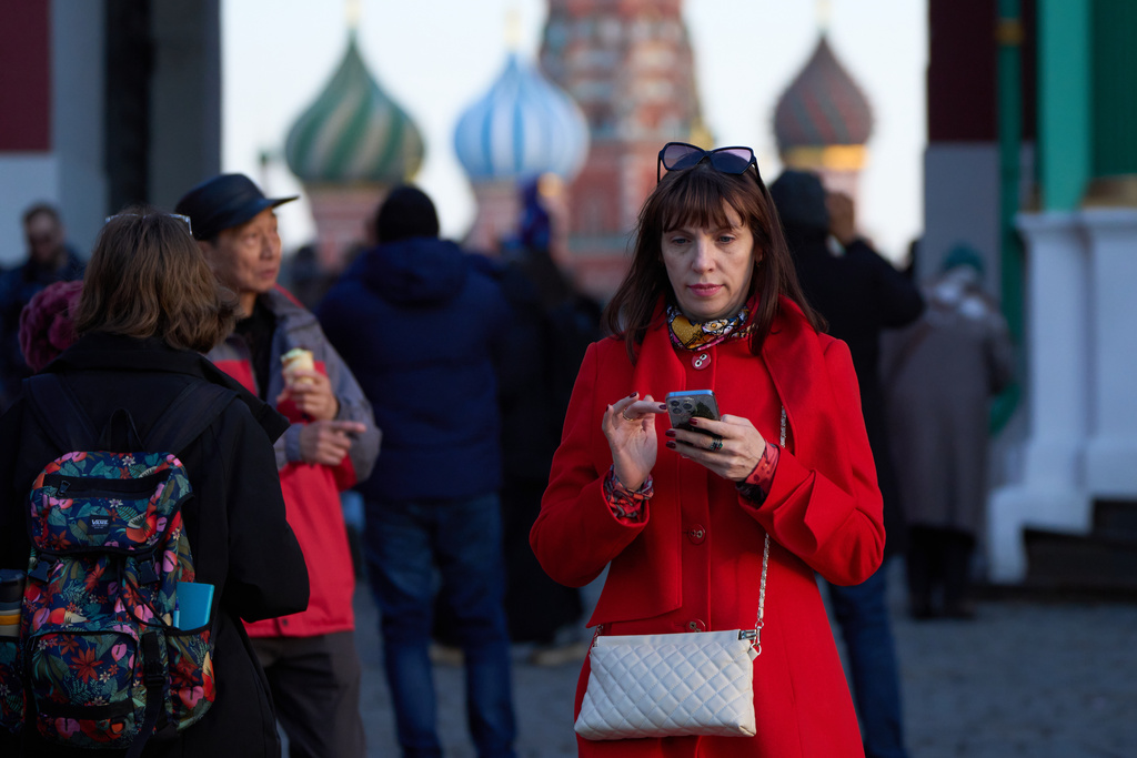 FILE - A woman holding her smartphone leaves Red Square in Moscow, on March 11, 2026. (AP Photo/Alexander Zemlianichenko, File)