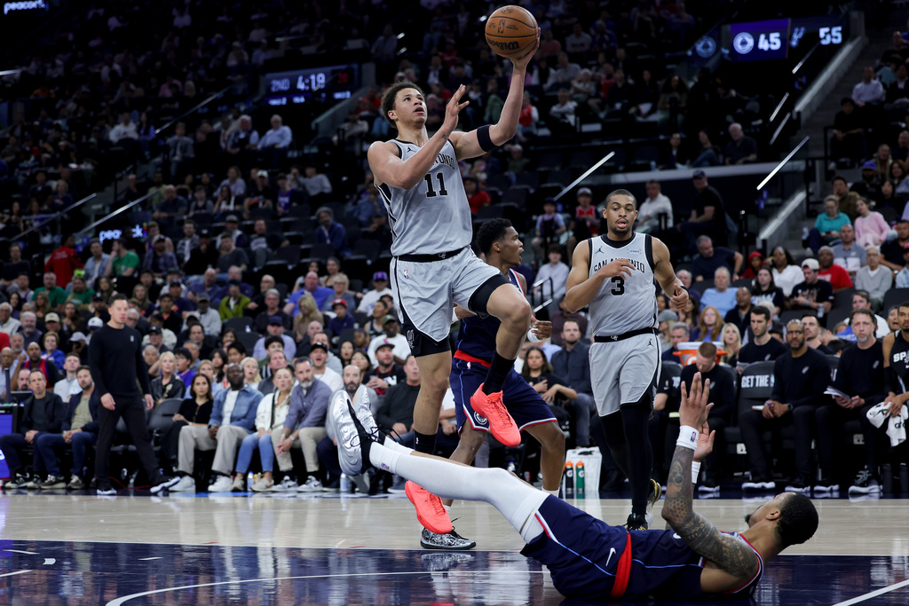 San Antonio Spurs forward Carter Bryant (11) is fouled by Los Angeles Clippers forward John Collins, bottom, during the first half of an NBA basketball game Monday, March 16, 2026, in Inglewood, Calif. (AP Photo/Ryan Sun)