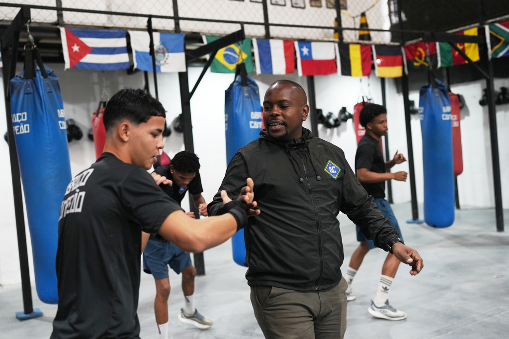 Owner Alan Duarte greets a youth at Abraco Campeao, or Embrace Champions, an academy that offers free boxing, jiu-jitsu, Muay Thai and capoeira classes, as well as educational talks on topics ranging from environmental issues to relationships, in the Complexo de Alemao favela in Rio de Janeiro, Wednesday, Sept. 16, 2026. (AP Photo/Silvia Izquierdo)