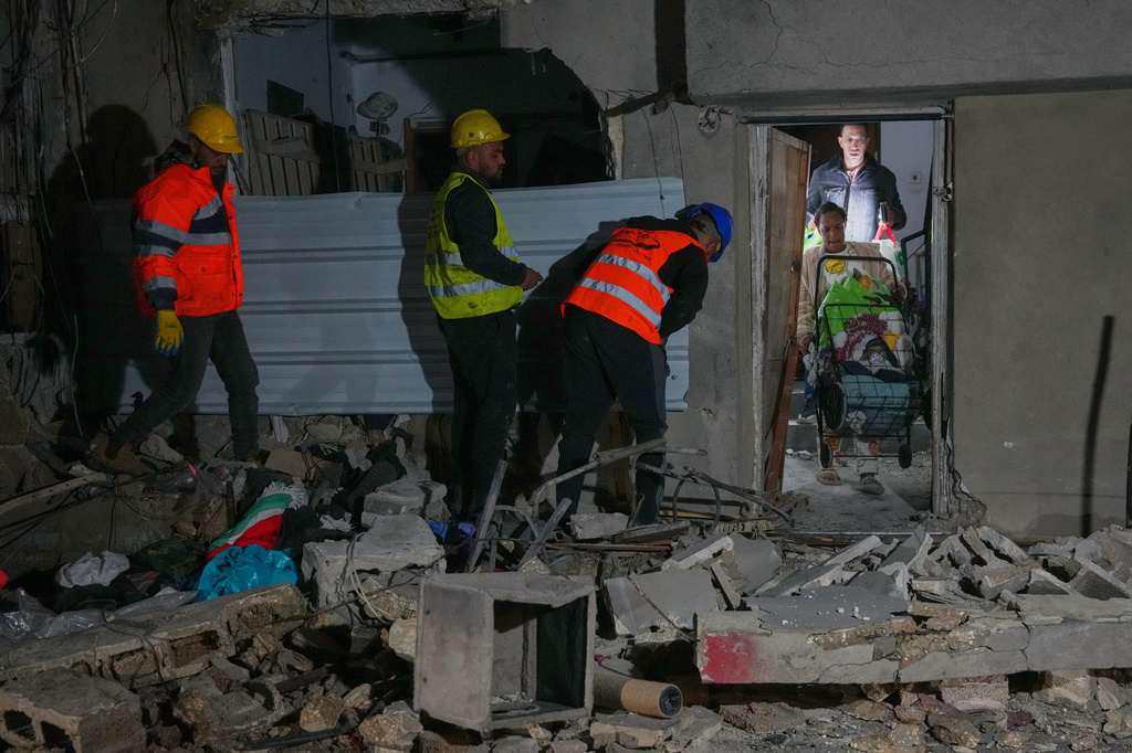 Residents carry personal belongings as they leave a building damaged in a missile strike in Tel Aviv, Israel, early Saturday, March 28, 2026. (AP Photo/Maya Levin)