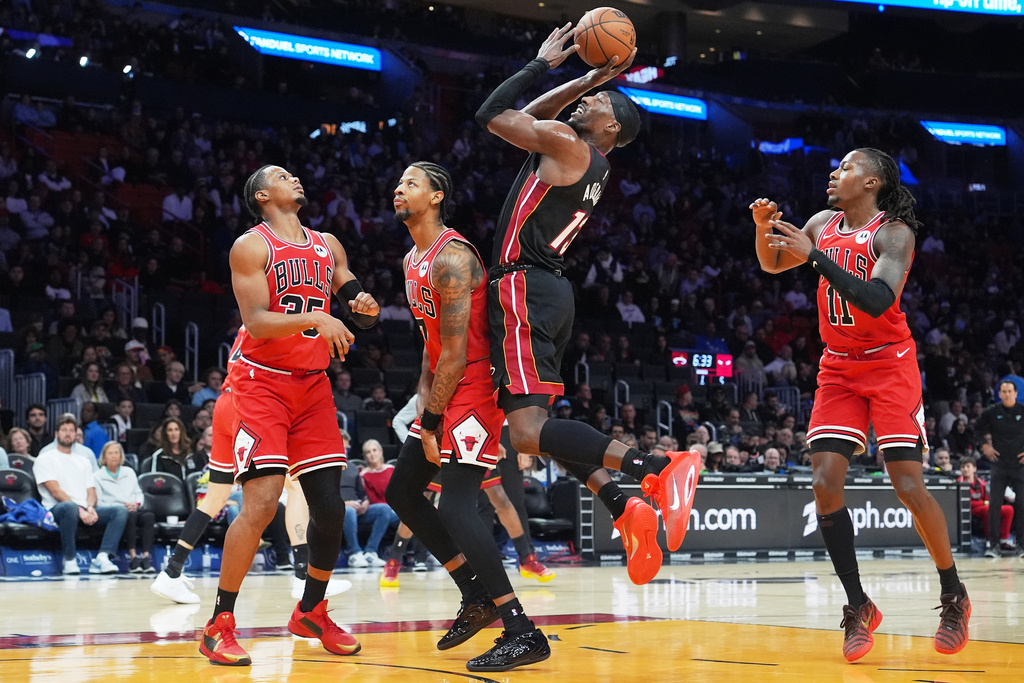 Miami Heat center Bam Adebayo (13) shoots over Chicago Bulls forward Isaac Okoro (35), forward Dalen Terry (7) and guard Ayo Dosunmu (11) during the first half of an NBA basketball game, Sunday, Feb. 1, 2026, in Miami. (AP Photo/Lynne Sladky)