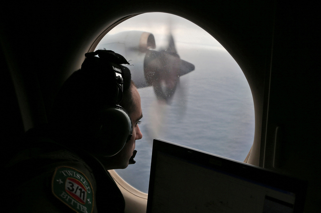 FILE - Flight officer Rayan Gharazeddine scans the water in the southern Indian Ocean off Australia from a Royal Australian Air Force AP-3C Orion during a search for the missing Malaysia Airlines Flight MH370 on March 22, 2014. (AP Photo/Rob Griffith, File)wld