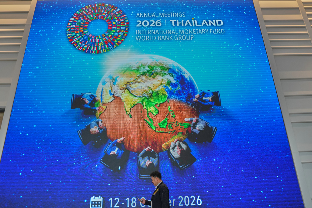 A man walks in front of giant billboard at the Queen Sirikit National Convention Center ahead of the annual meetings of the International Monetary Fund (IMF) and the World Bank Group in Bangkok, Thailand, Friday, Oct. 9, 2026. (AP Photo/Sakchai Lalit)