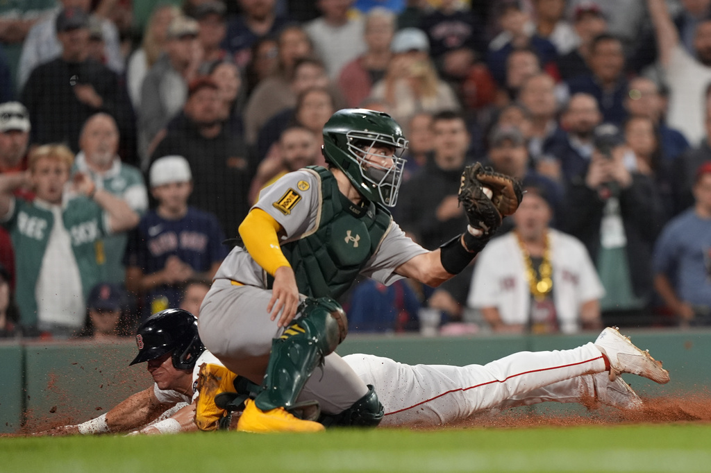 Boston Red Sox Nate Eaton, back, dives home for the winning run in the 10th inning past Athletics catcher Shea Langeliers in a baseball game, Wednesday, Sept. 17, 2025, in Boston. (AP Photo/Robert F. Bukaty)