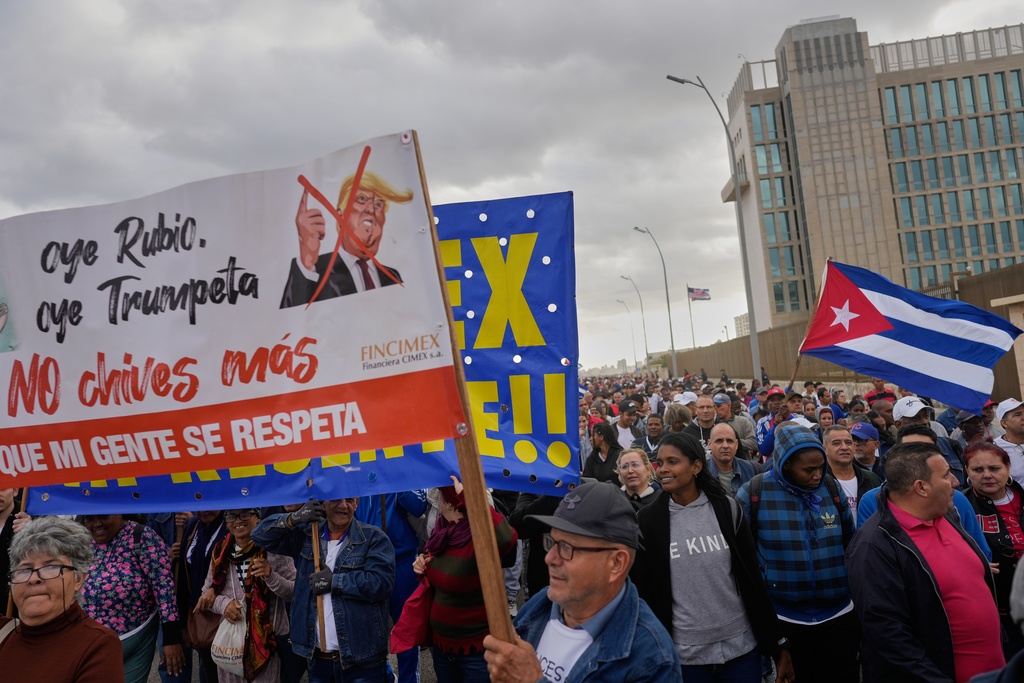 People holding a banner against President Donald Trump, march outside the U.S. Embassy to protest the killing of Cuban officers during the U.S. operation that captured Venezuelan President Nicolas Maduro, in Havana, Cuba, Friday, Jan. 16, 2026. (AP Photo/Ramon Espinosa)
