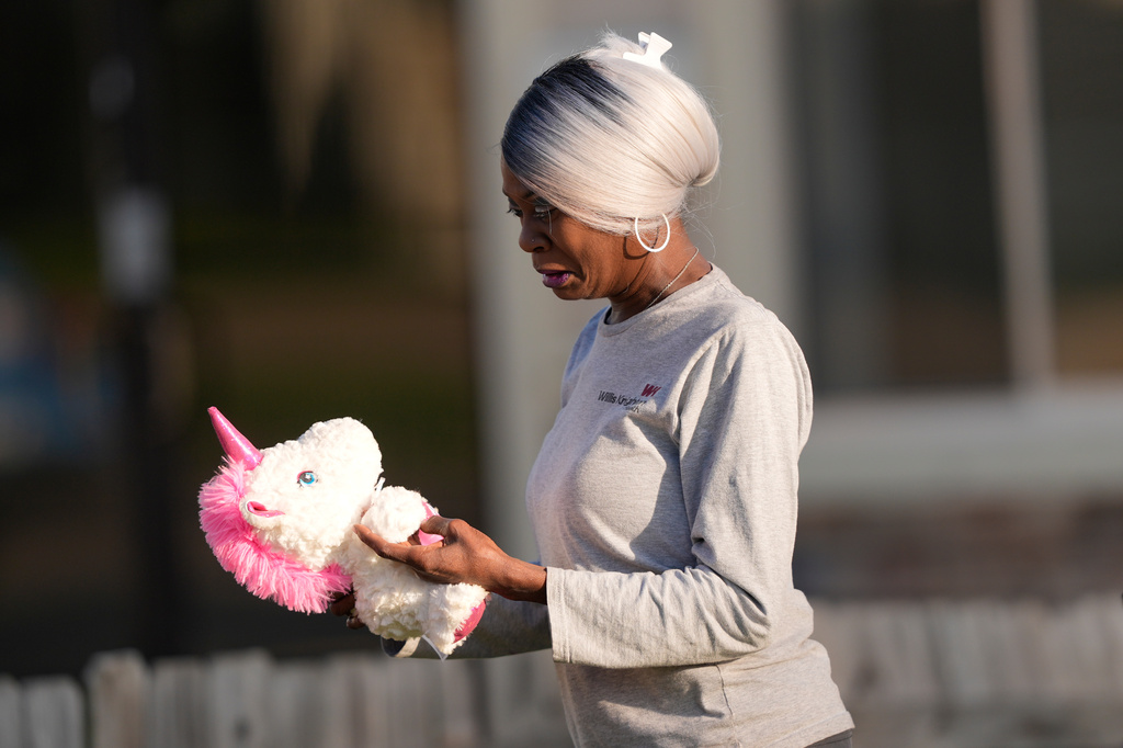 A woman holds a stuffed unicorn upon arriving at the scene of a mass shooting, Sunday, April 19, 2026, in Shreveport, La. (AP Photo/Gerald Herbert)