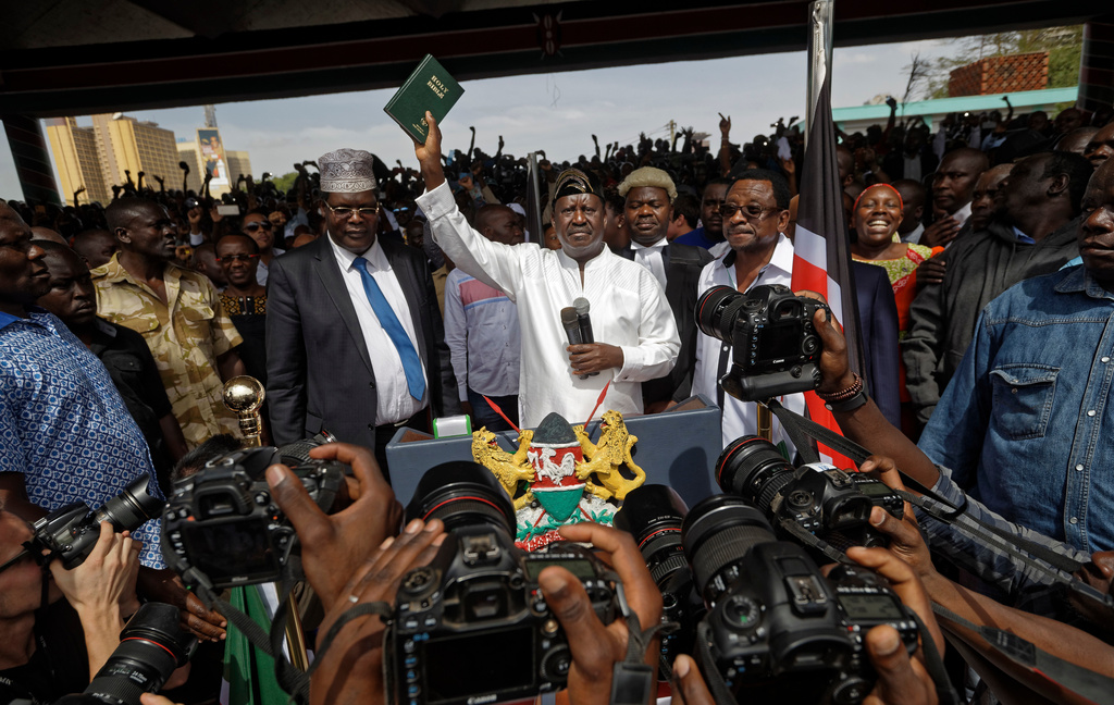 Opposition leader Raila Odinga holds a bible aloft after swearing an oath during a mock "swearing-in" ceremony at Uhuru Park in downtown Nairobi, Kenya, Tuesday, Jan. 30, 2018. (AP Photo/Ben Curtis)