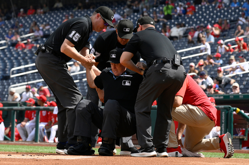 Home plate umpire Todd Tichenor, center, is helped up after being hit by a foul tip by Los Angeles Angels' Wade Meckler during the first inning of a baseball game between the Washington Nationals and the Angels, Sunday, Sept. 13, 2026, in Washington. (AP Photo/Nick Wass)