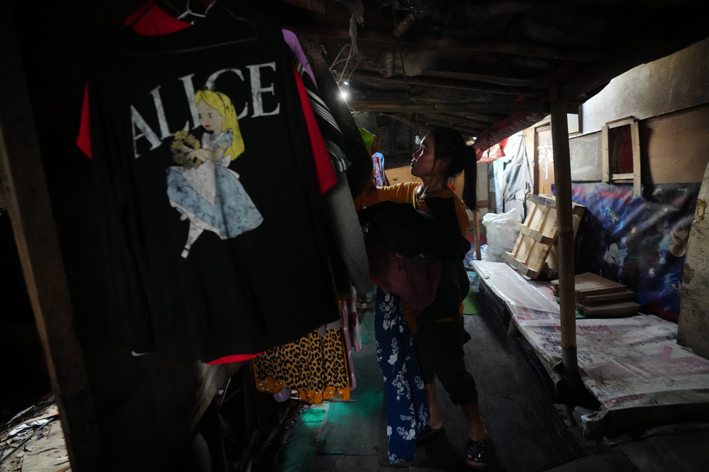 Nur Wencih, a waste picker, takes down her dry clothes at her boarding house near the Bantargebang landfill on the outskirts of Jakarta, Indonesia, Monday, July 6, 2026. (AP Photo/Tatan Syuflana)