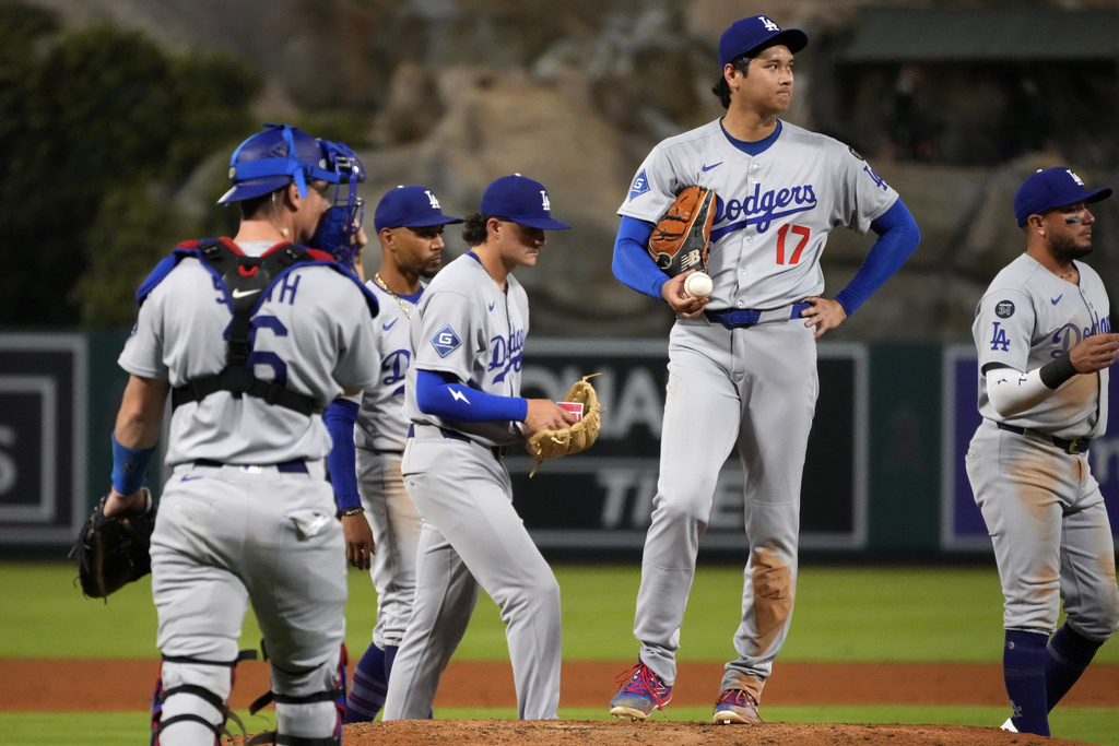 Los Angeles Dodgers starting pitcher Shohei Ohtani, second from right, waits to be taken out of the game throws to the plate during the fifth inning of a baseball game against the Los Angeles Angels, Wednesday, Aug. 13, 2025, in Anaheim, Calif. (AP Photo/Mark J. Terrill)
