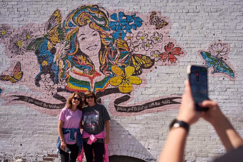 Christy Oakes, left, and Beth Sloan, right, of Kentucky pose with a mural of Dolly Parton Friday, Sept. 25, 2026, in Nashville, Tenn. during Dolly Parton Day honoring the late country music artist. (AP Photo/George Walker IV)