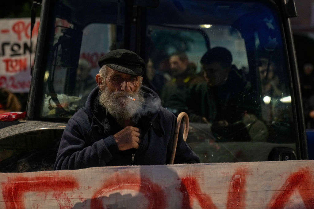 A farmer smokes a cigarette as he stands in front of a tractor outside the Greek Parliament during a protest against high production costs, low prices for their products, and delays in subsidy payments, in central Athens on Friday, Feb. 13, 2026. (AP Photo/Petros Giannakouris)