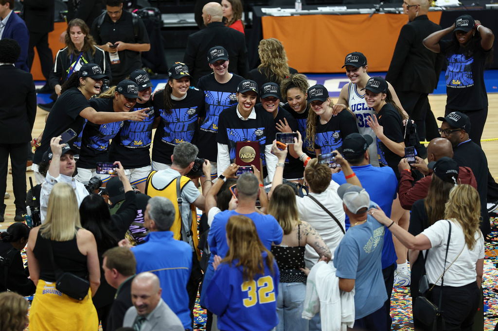 UCLA players take a photo with the Sacramento Regional trophy during post game celebrations after winning the Elite Eight of the NCAA college basketball tournament against Duke Sunday, March 29, 2026, in Sacramento, Calif. (AP Photo/Sara Nevis)