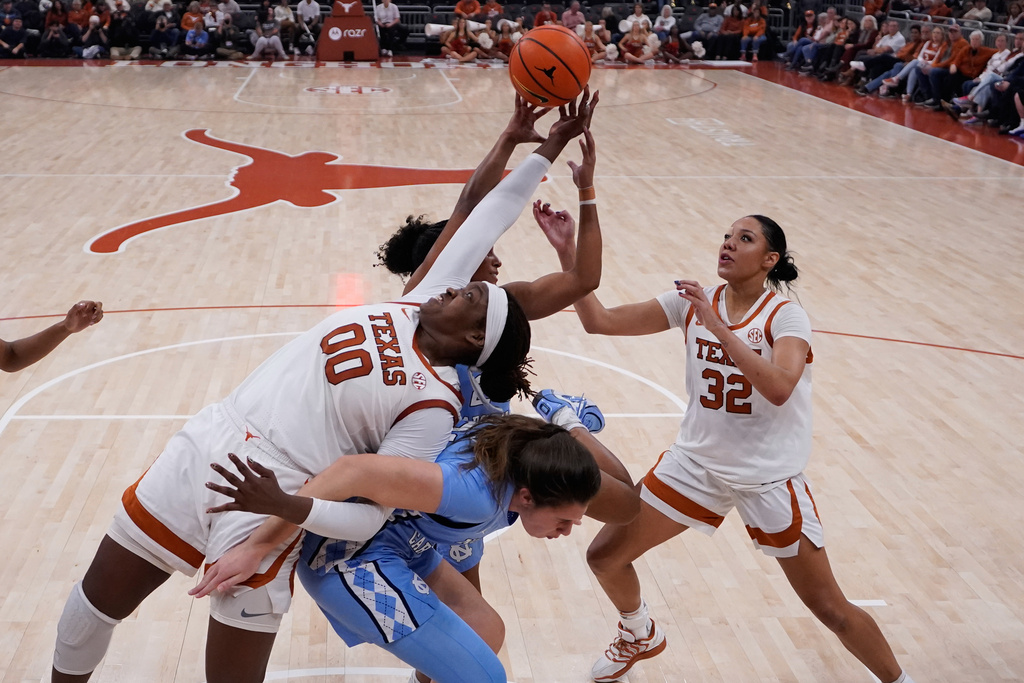 Texas center Kyla Oldacre (00) battles North Carolina guard Indya Nivar, rear, and forward Ciera Toomey, center, for a rebound during the second half of an NCAA college basketball game in Austin, Texas, Thursday, Dec. 4, 2025. (AP Photo/Eric Gay)