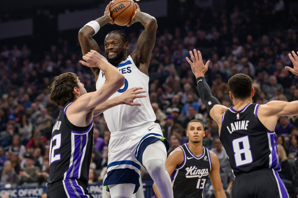 Minnesota Timberwolves forward Julius Randle passes the ball over Sacramento Kings center Maxime Raynaud during the first half of an NBA basketball game in Sacramento, Calif., Monday, Nov. 24, 2025. (AP Photo/Randall Benton)