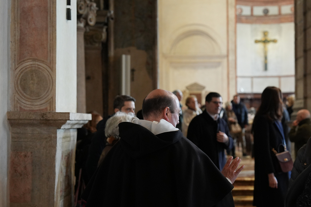 A friar of the Dominican community speaks with visitors in the Basilica of Santa Maria delle Grazie, best known as the home of Leonardo da Vinci's "The Last Supper," in Milan, Italy, Sunday, Feb. 15, 2026. (AP Photo/María Teresa Hernández)