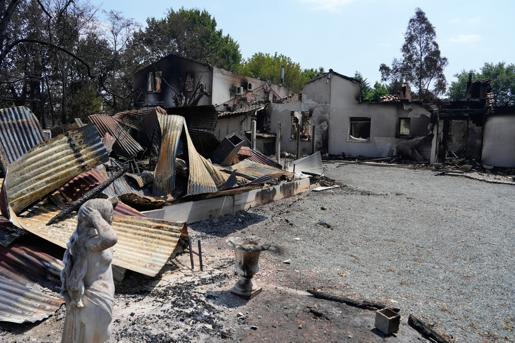 A statue stands in front of the remains of a house after wildfires raged in the village of Le Porge, on the Bay of Biscay, France, Monday, July 27, 2026. (AP Photo/Baz Ratner)