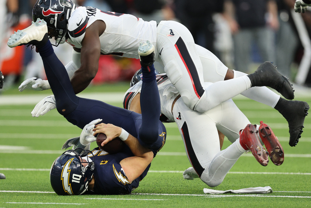 Los Angeles Chargers quarterback Justin Herbert, bottom left, is sacked by Houston Texans linebacker Henry To'Oto'O during the second half of an NFL football game Saturday, Dec. 27, 2025, in Inglewood, Calif. (AP Photo/Kevork Djansezian)