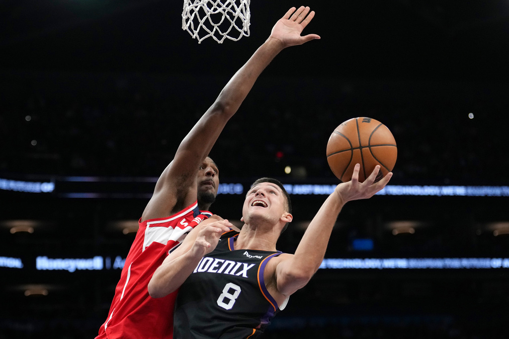 Phoenix Suns guard Grayson Allen (8) gets off a shot against Washington Wizards center Alex Sarr during the first half of an NBA basketball game, Sunday, Jan. 11, 2026, in Phoenix. (AP Photo/Ross D. Franklin)