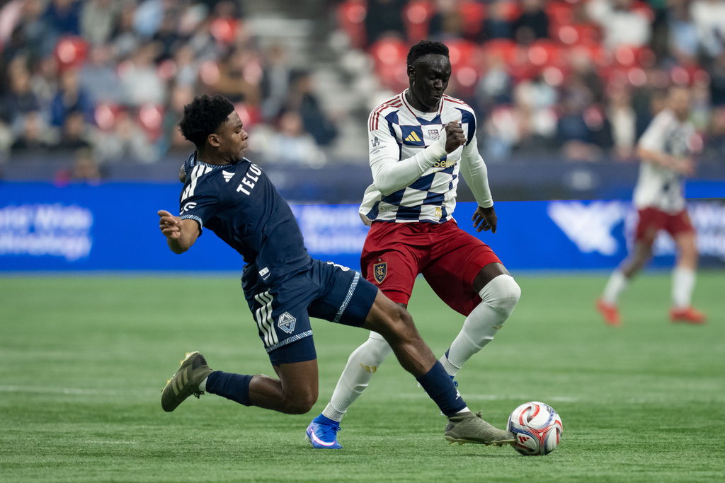 Vancouver Whitecaps' Ralph Priso (left) and Real Salt Lake's Ariath Piol (19) vie for the ball during the first half of an MLS soccer match in Vancouver, on Saturday, Feb. 21, 2026. (Ethan Cairns/The Canadian Press via AP)