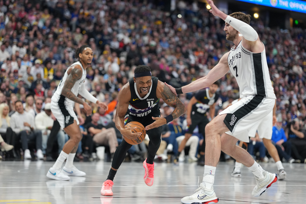 Denver Nuggets guard Bruce Brown, left, reacts after being injured while driving past San Antonio Spurs forward Luke Kornet in the second half of an NBA basketball game Saturday, April 4, 2026, in Denver. (AP Photo/David Zalubowski)