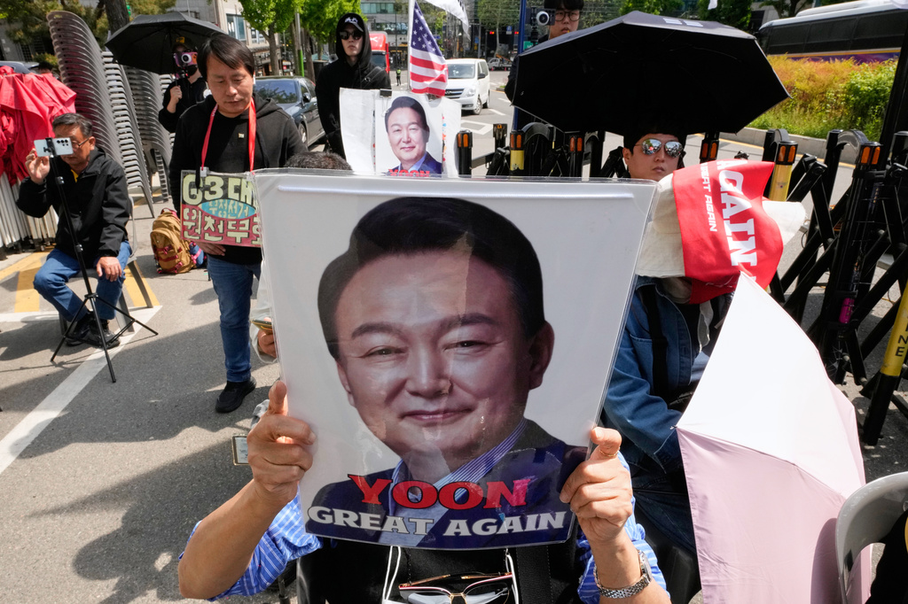 A supporter of former South Korean President Yoon Suk Yeol holds up his portrait during a rally outside of the Seoul High Court in Seoul, South Korea, Wednesday, April 29, 2026. (AP Photo/Ahn Young-joon)