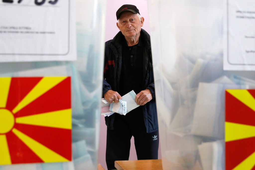 A man holding his ballot paper is pictured between ballot boxes during the local elections, at a polling station in Skopje, North Macedonia, on Sunday, Oct. 19, 2025. (AP Photo/Boris Grdanoski)