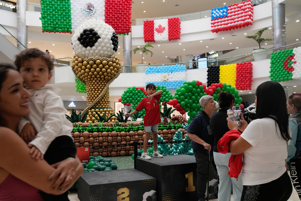 Shoppers stand in front of balloon flags of countries participating in the FIFA World Cup finals at a shopping center in Guadalajara, Mexico, Tuesday, June 9, 2026. (AP Photo/Matias Delacroix)